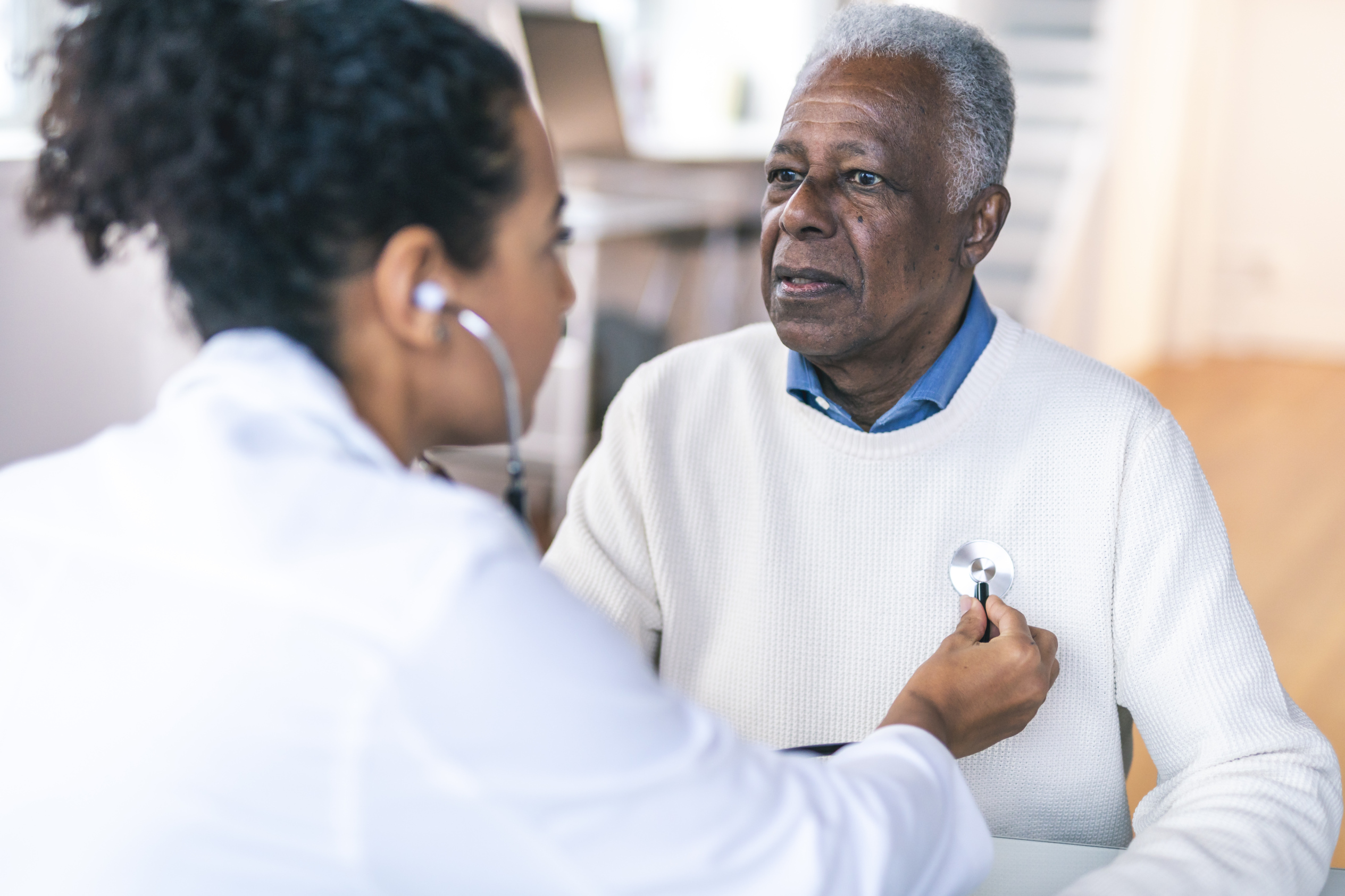 A doctor listening to a man's heart with a stethoscope.